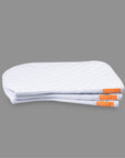 A pile of three white perfecto saddle pads with an orange logo tag along the seam.