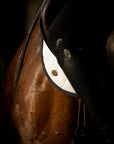 A moody shot of a chestnut horse wearing a white Jackie&Co saddle pad.