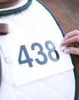 Jackie&Co lucky number pins being used to pin a competition number to a saddle pad on a chestnut horse.
