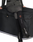 A women in black Jackie&Co riding socks sitting on a trunk covered in a black cover.