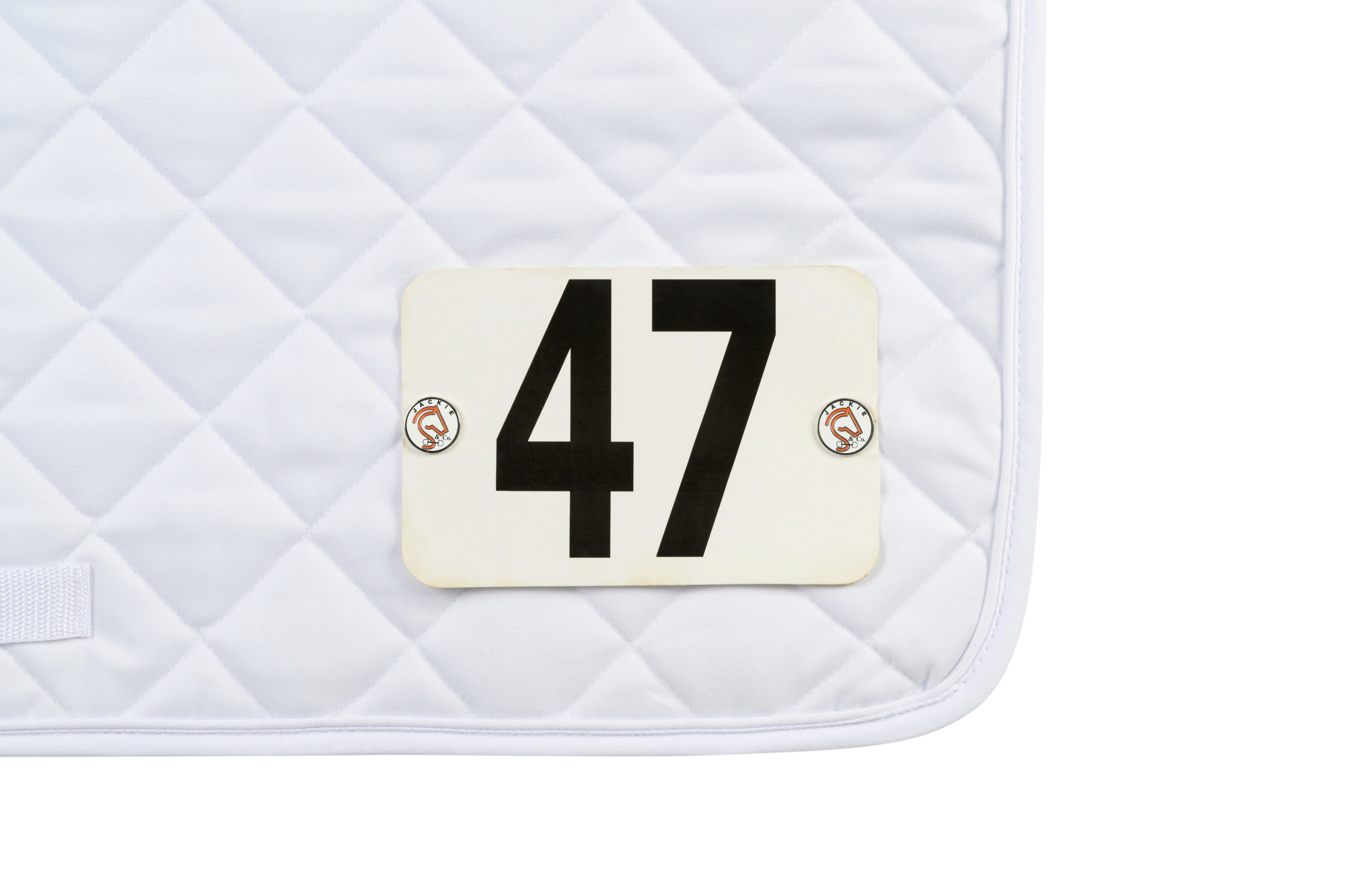 Jackie&Co Lucky Numbers pins holding competition numbers to a white saddle pad. 